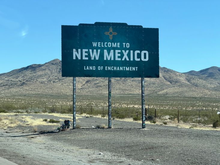 Welcome to New Mexico highway sign on a sunlit desert road